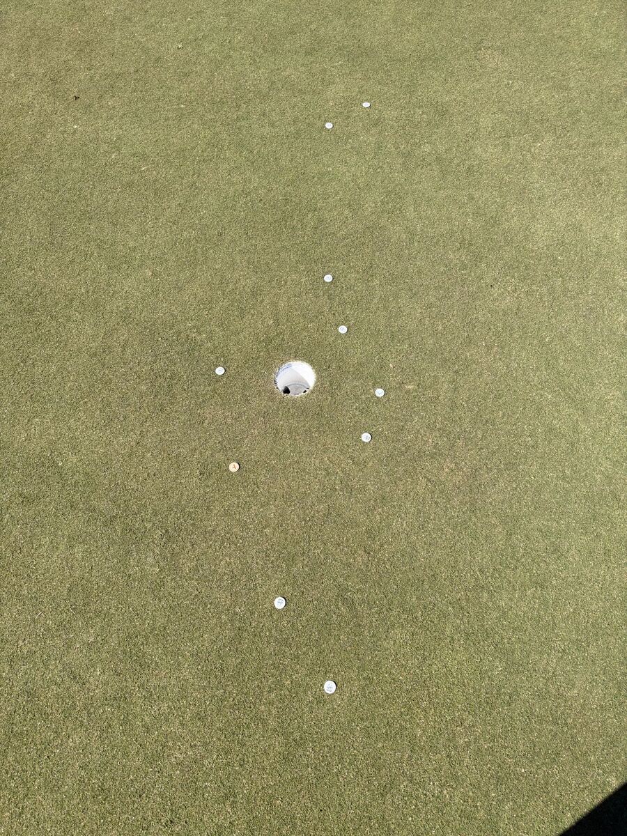 Overhead view of ball markers showing the spread of ten putts around the cup